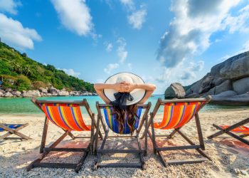 mulher-com-chapeu-sentado-na-praia-de-cadeiras-na-bela-praia-tropical-mulher-relaxando-em-uma-praia-tropical-na-ilha-de-koh-nangyuan